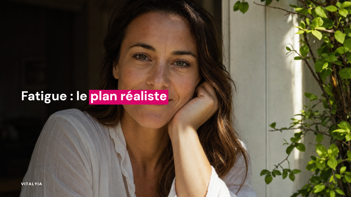 Une femme souriante en chemise blanche est assise près d'une fenêtre avec des plantes vertes à côté