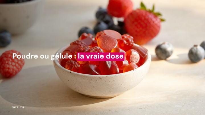 Des gummies rouges dans une coupelle en céramique sur une table crème, entourés de fruits rouges et bleus.